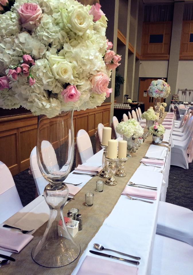 Pastel wedding reception head table with peach and white roses and pastel center pieces