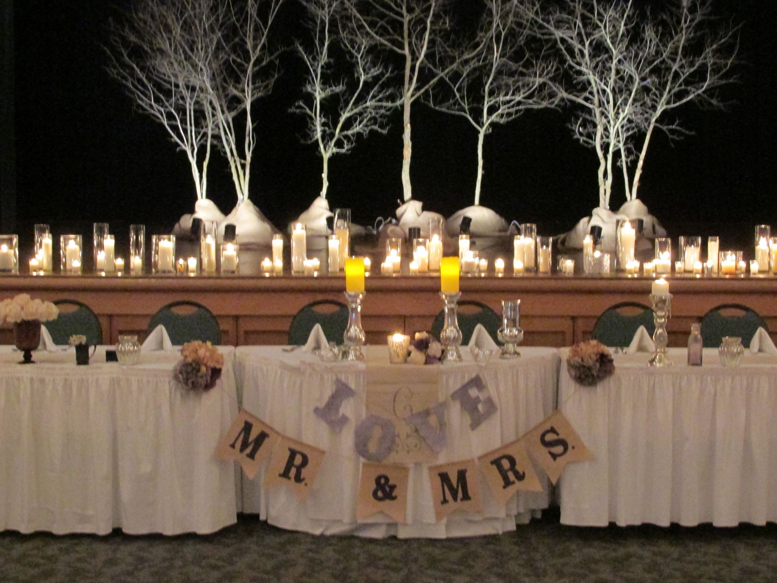 Winter white wedding reception head table with love and mr and mrs signs with white tree branches in